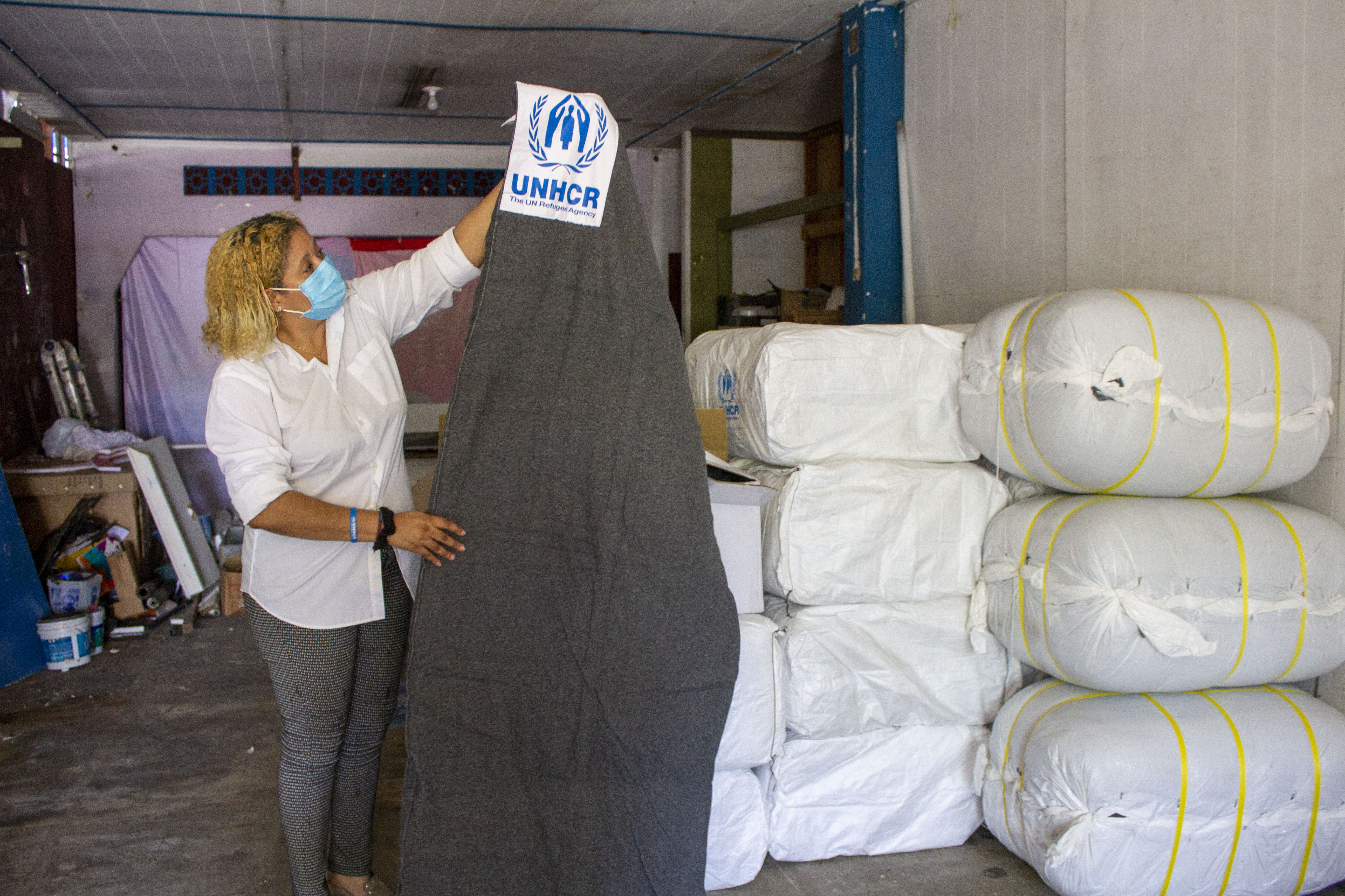 The founder of La Casita holds up a blanket donated by UNHCR