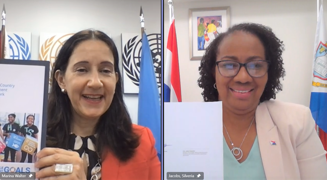 UN Resident Coordinator, Marina Walter (left), and Prime Minister of Sint Maarten, the Honourable Silveria Jacobs (right), display their signed copies of the MSDCF during a virtual signing ceremony.