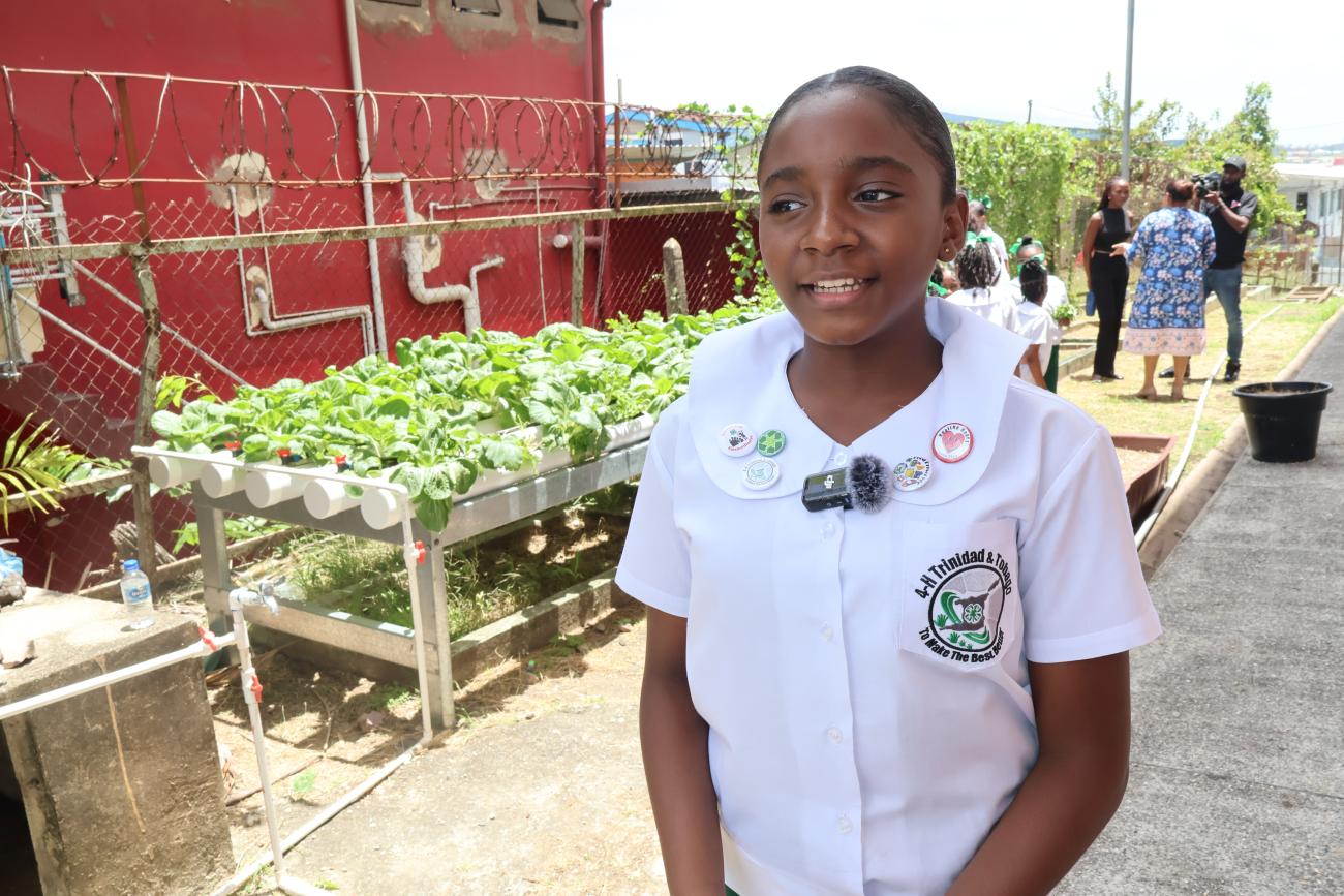 A female student wearing her uniform stands in her school aquaponics uniform