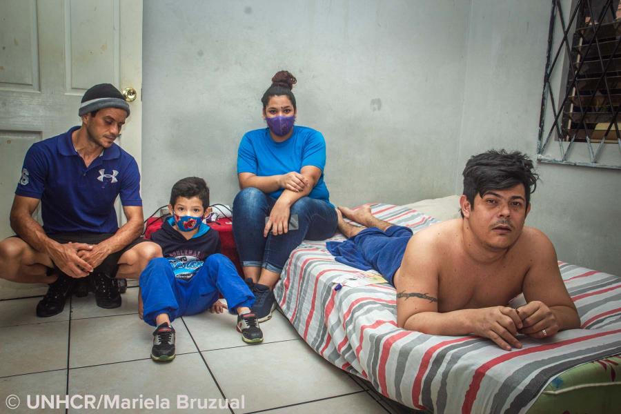 Erwin, his wife Yanitza, his son Emanuel and his brother Johan sit in Erwin's apartment in El Dorado, Trinidad and Tobago.