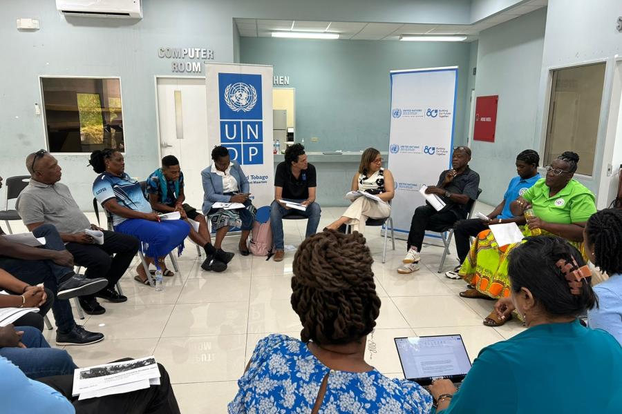 a group of people sitting on chairs in a circle, having a conversation