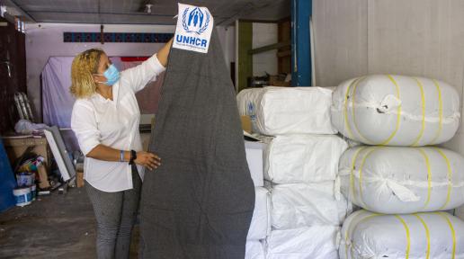 The founder of La Casita holds up a blanket donated by UNHCR